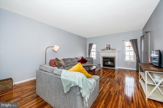 living area with a fireplace with flush hearth, baseboards, and wood finished floors