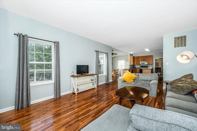 living room featuring visible vents, baseboards, and wood finished floors