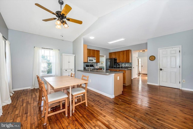 kitchen featuring electric range oven, freestanding refrigerator, a peninsula, brown cabinets, and white microwave