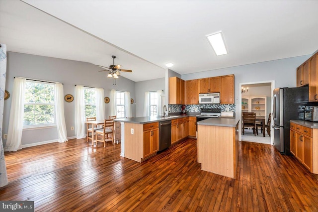 kitchen with lofted ceiling, a peninsula, backsplash, dark wood finished floors, and appliances with stainless steel finishes