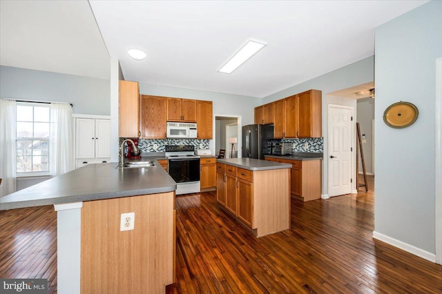 kitchen featuring white microwave, freestanding refrigerator, range with electric stovetop, decorative backsplash, and a sink