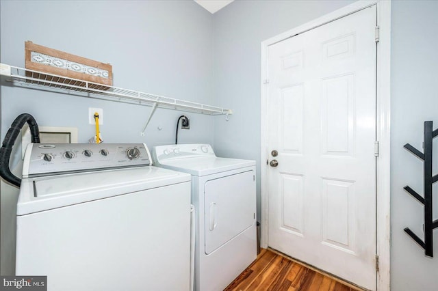 clothes washing area with washing machine and dryer, dark wood-style flooring, and laundry area