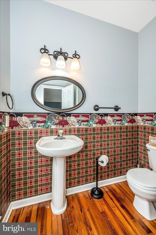 bathroom with toilet, wood finished floors, and a wainscoted wall