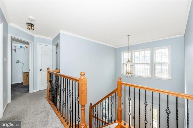 hallway with ornamental molding, baseboards, an upstairs landing, and carpet flooring