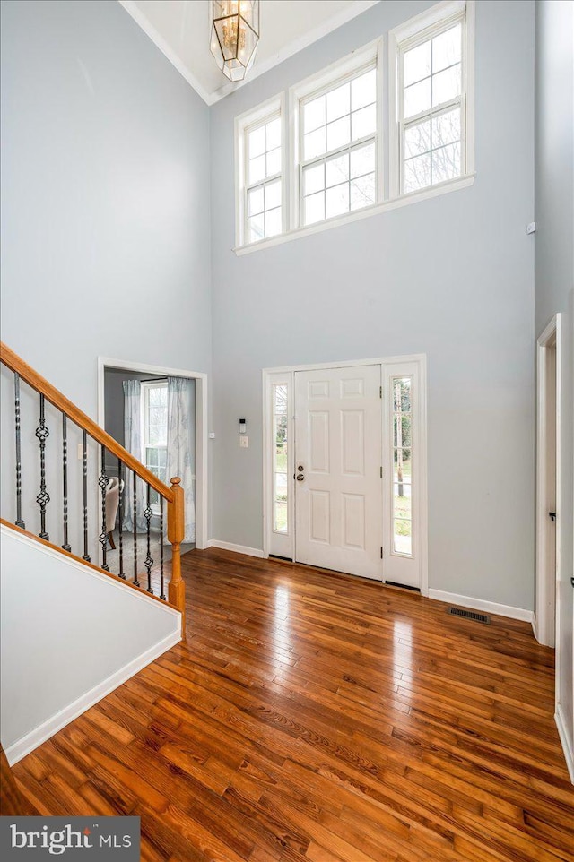 foyer featuring stairway, a wealth of natural light, wood finished floors, and a towering ceiling