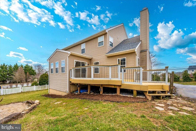 back of property featuring fence, a yard, a deck, and a chimney