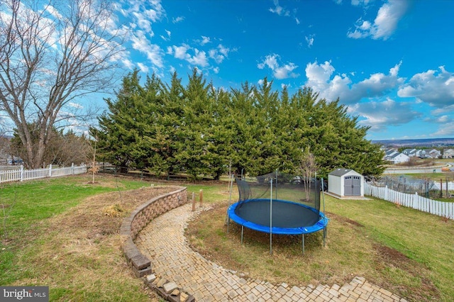 view of yard with a storage shed, a fenced backyard, a trampoline, and an outdoor structure