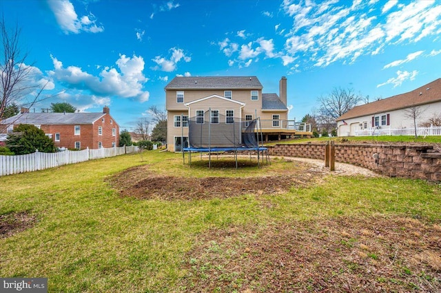 back of house with a yard, fence, and a trampoline