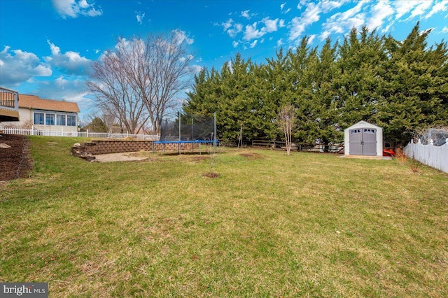 view of yard with a trampoline, a storage shed, a fenced backyard, and an outbuilding