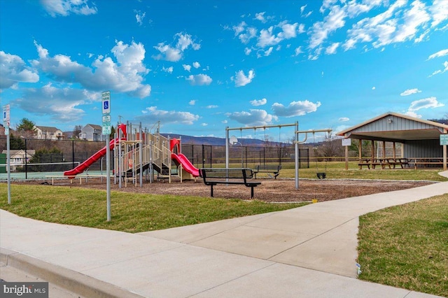 communal playground featuring a yard and fence