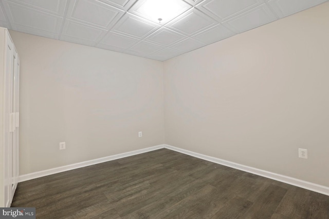 unfurnished room featuring an ornate ceiling, dark wood-style flooring, and baseboards