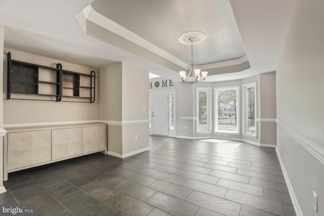 unfurnished room with an inviting chandelier, a raised ceiling, and baseboards