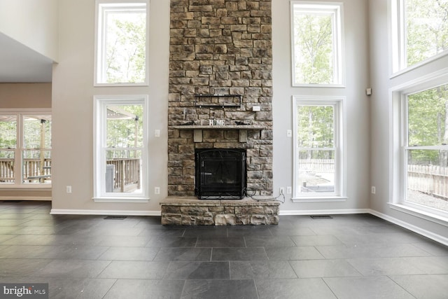 unfurnished living room featuring a high ceiling, visible vents, and baseboards