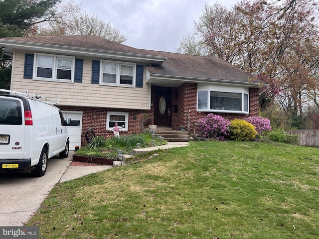 tri-level home with a front lawn, fence, brick siding, a shingled roof, and concrete driveway