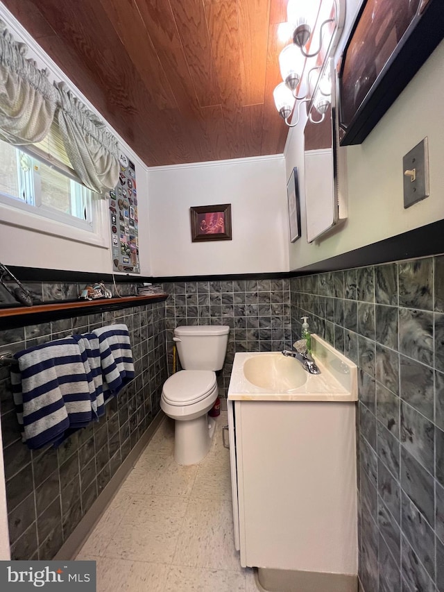 bathroom with tile walls, wooden ceiling, tile patterned floors, a wainscoted wall, and toilet