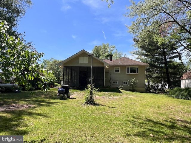 rear view of house with a yard and a sunroom