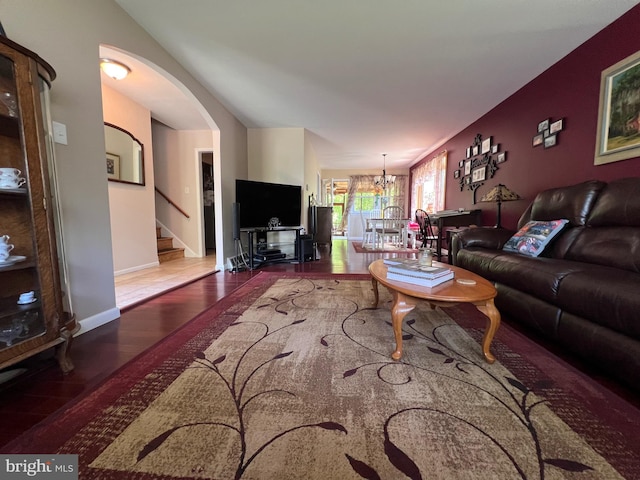 living area with arched walkways, wood finished floors, stairway, baseboards, and an inviting chandelier