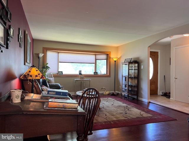 office with arched walkways, baseboards, and hardwood / wood-style flooring