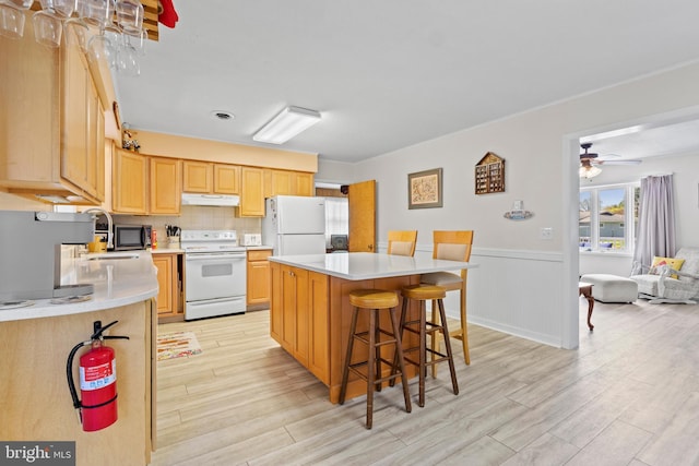 605 Old Post Ct, Bethany Beach, DE 19930 - kitchen featuring light wood-style flooring, a kitchen breakfast bar, under cabinet range hood, and white appliances