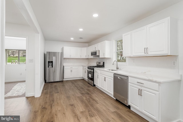 kitchen featuring appliances with stainless steel finishes, a sink, backsplash, and plenty of natural light