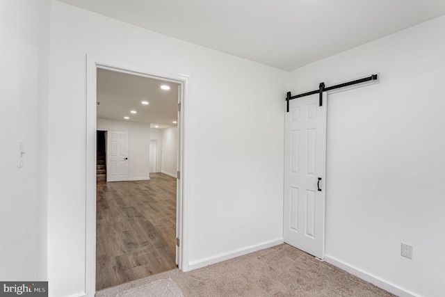 unfurnished room featuring baseboards, a barn door, and recessed lighting