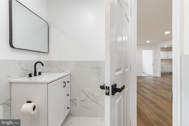 bathroom featuring vanity, recessed lighting, a wainscoted wall, wood finished floors, and tile walls