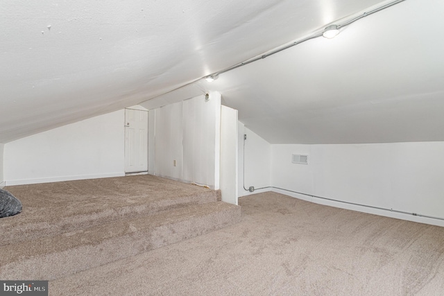 additional living space with carpet floors, baseboards, visible vents, and lofted ceiling