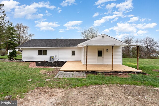 back of property with a yard, a shingled roof, and central AC