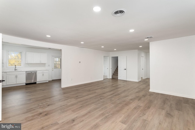 unfurnished living room with visible vents, stairway, recessed lighting, light wood finished floors, and baseboards