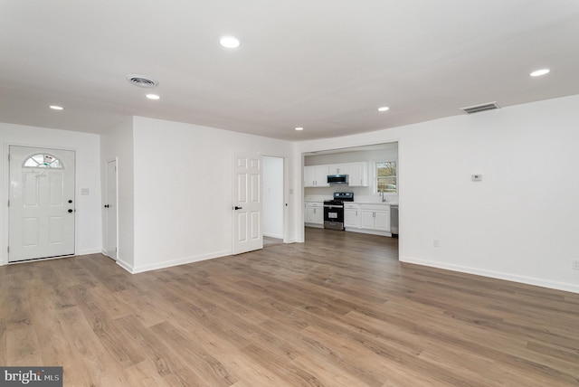 unfurnished living room with light wood finished floors, baseboards, visible vents, and recessed lighting
