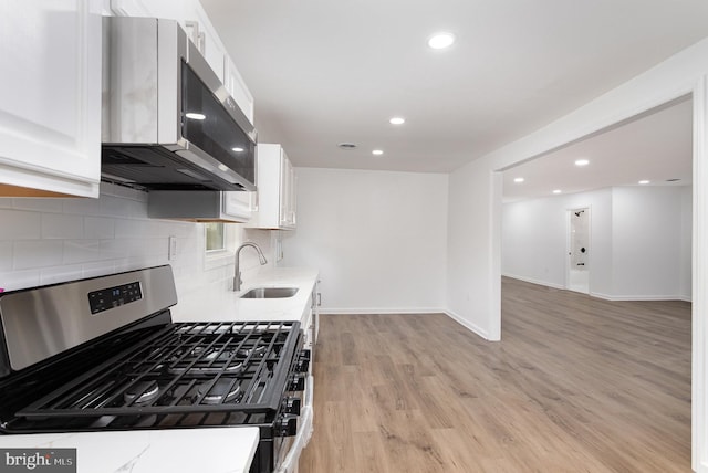 kitchen with white cabinets, recessed lighting, a sink, stainless steel appliances, and decorative backsplash
