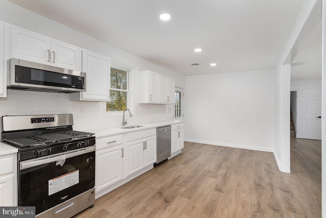 kitchen with light countertops, decorative backsplash, a sink, and stainless steel appliances