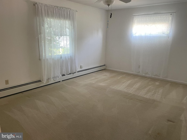 unfurnished room with baseboard heating, light colored carpet, ceiling fan, and plenty of natural light
