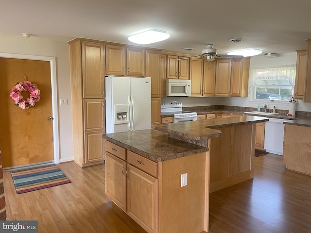 kitchen featuring white appliances, light wood-style floors, a center island, and dark countertops