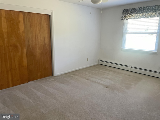 carpeted spare room with a baseboard radiator, ceiling fan, and baseboards