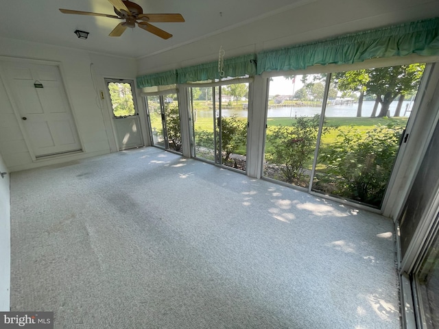 unfurnished sunroom featuring a water view, plenty of natural light, and a ceiling fan