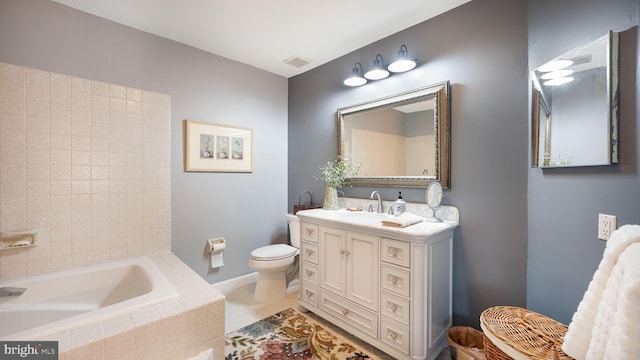 bathroom featuring vanity, visible vents, toilet, and tiled tub