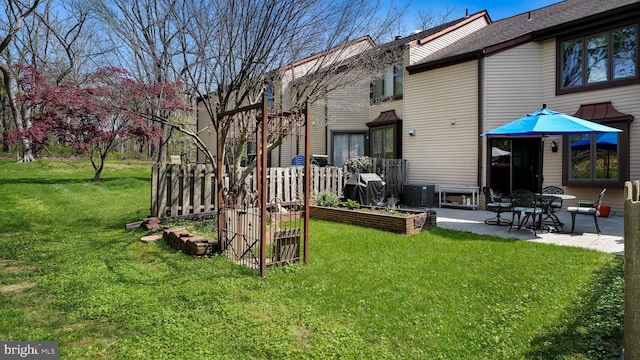 rear view of property with a patio, a vegetable garden, a yard, and central AC