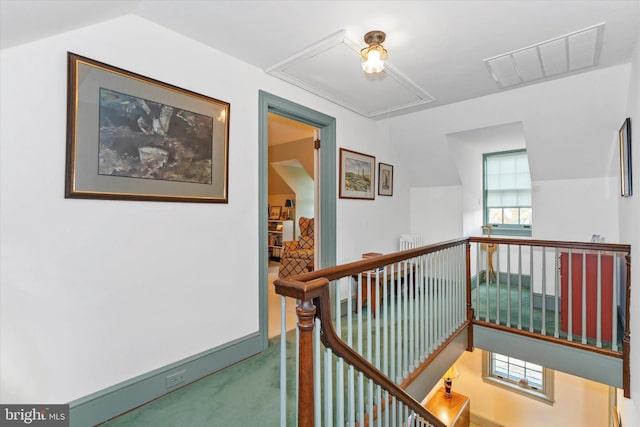 corridor featuring a wealth of natural light, an upstairs landing, visible vents, and attic access