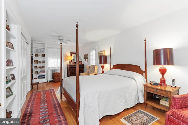 bedroom with ceiling fan, radiator, and wood finished floors