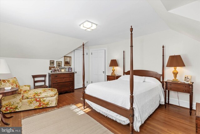 bedroom with wood finished floors and vaulted ceiling