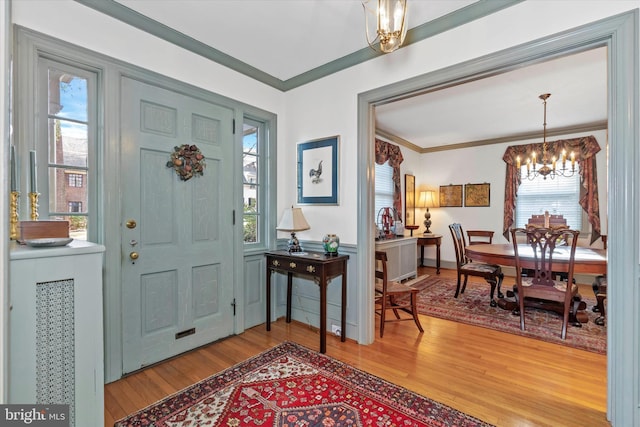 entrance foyer featuring crown molding, light wood finished floors, plenty of natural light, and a chandelier