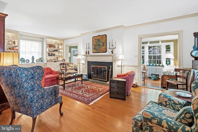 living room featuring a wealth of natural light, wood-type flooring, a brick fireplace, and radiator