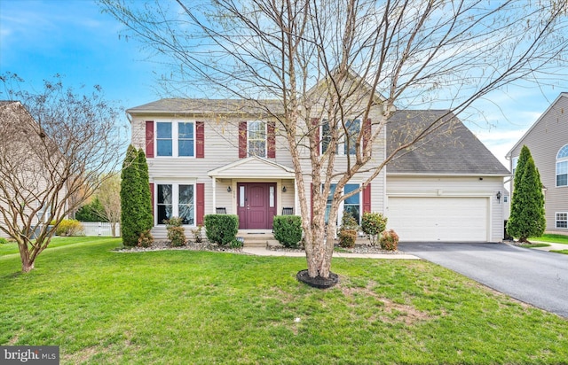 colonial home featuring a front yard, an attached garage, and aphalt driveway