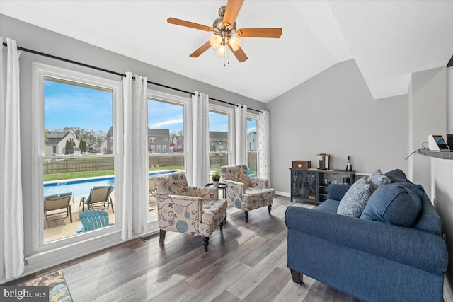 living area featuring light wood-style floors, a ceiling fan, and vaulted ceiling