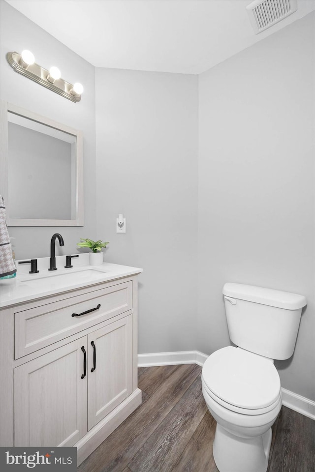 bathroom featuring visible vents, baseboards, toilet, and wood finished floors