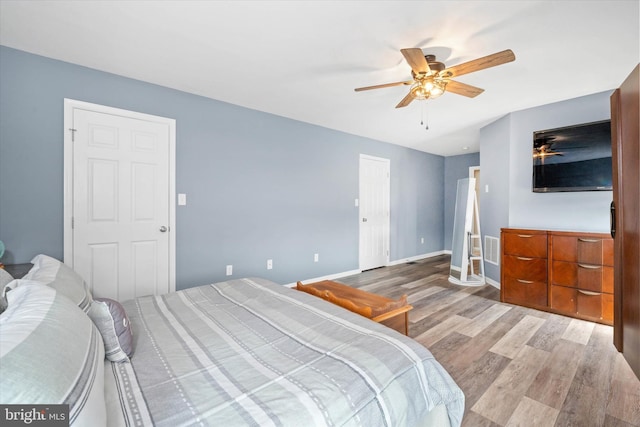 bedroom with wood finished floors, ceiling fan, baseboards, and visible vents