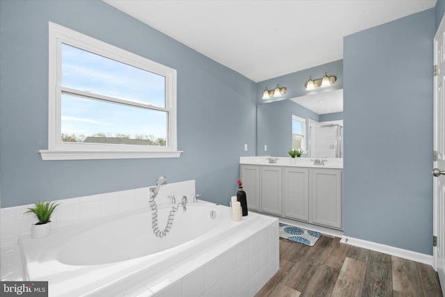 full bathroom with a sink, a bath, double vanity, and wood finished floors