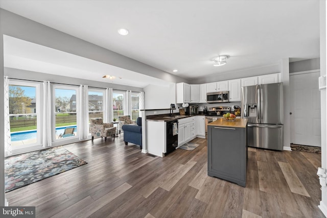 kitchen featuring appliances with stainless steel finishes, dark wood-style flooring, a sink, and white cabinetry