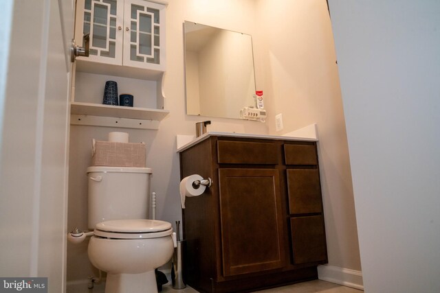 half bathroom with vanity, toilet, and baseboards